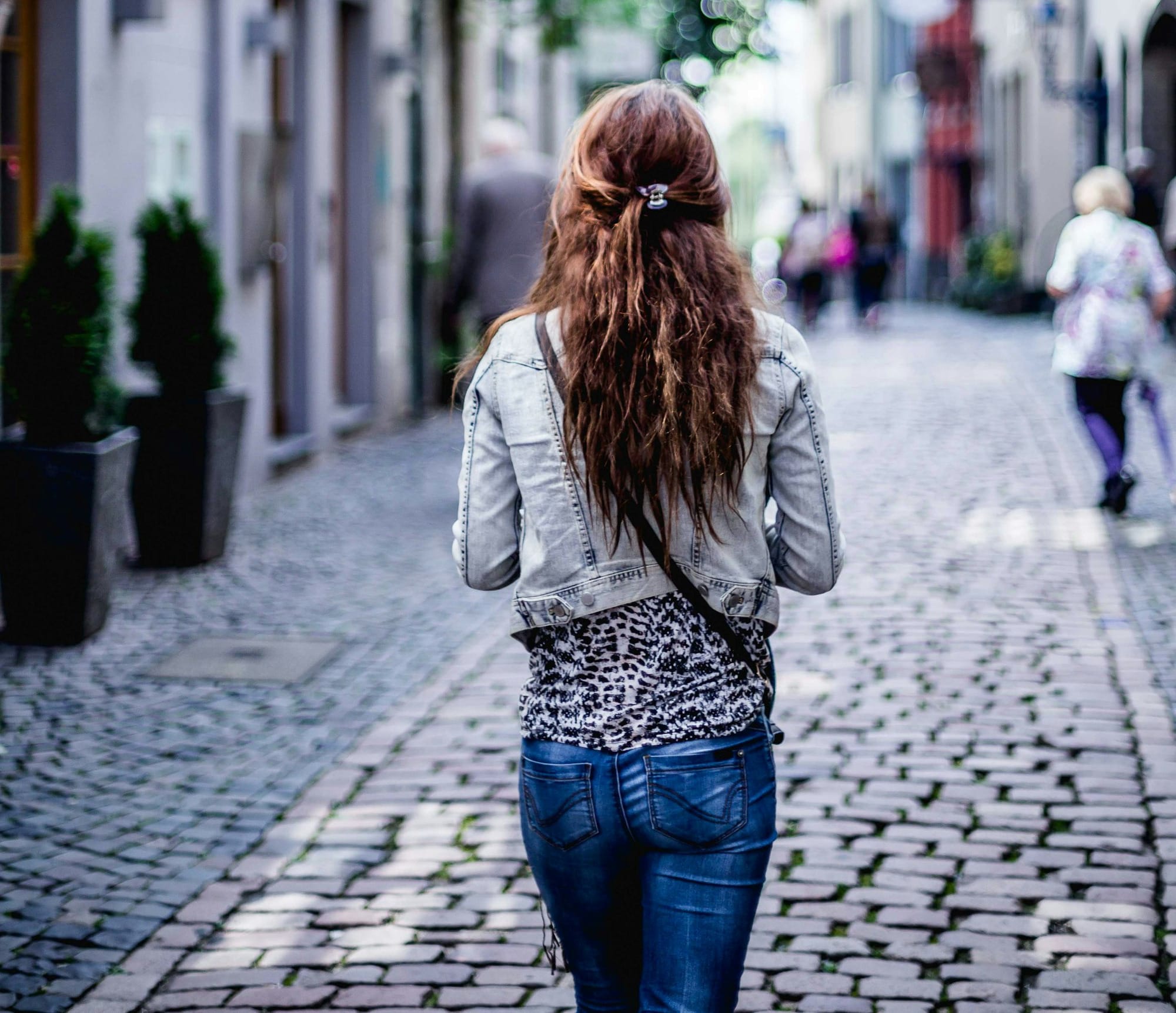 woman wearing gray top walking on sidewalk during daytime