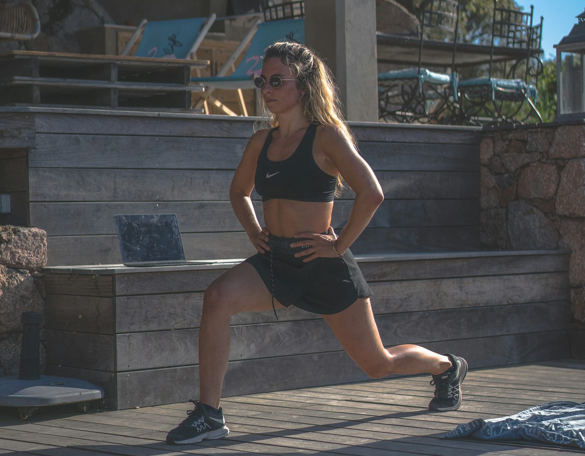 woman in black sports bra and black shorts sitting on concrete bench during daytime